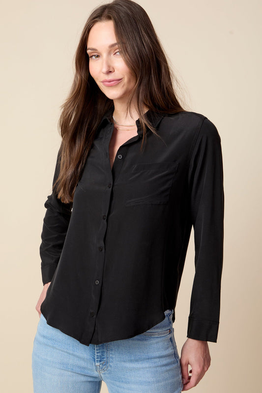 Woman wearing a black shirt and blue jeans against a beige background
