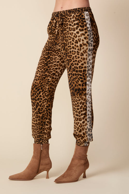 Leopard print pants worn by a person on a beige background