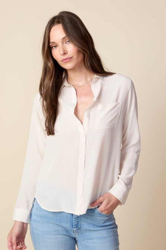 Woman wearing a white blouse and light blue jeans against a beige background