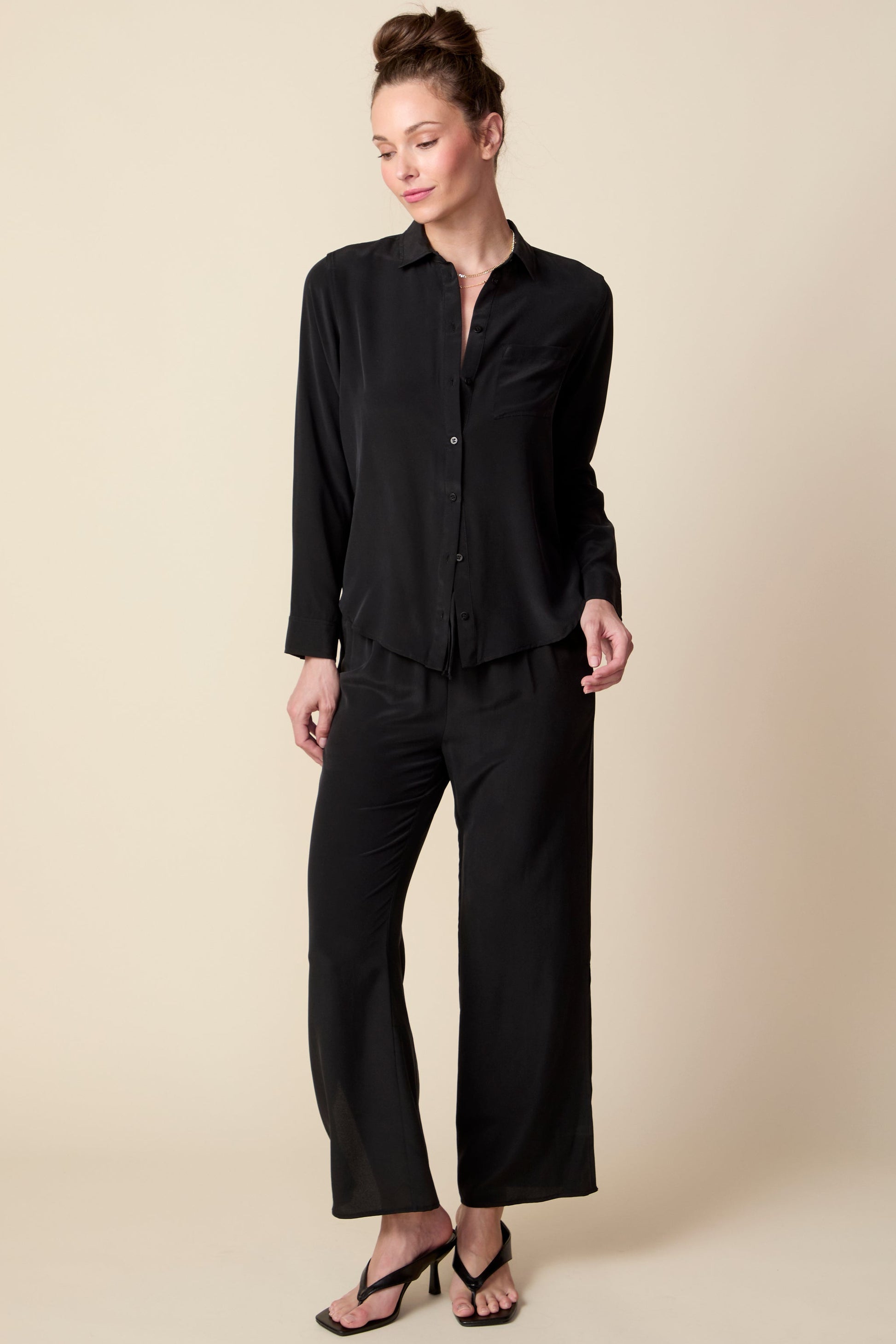 Woman wearing a black outfit on a beige background