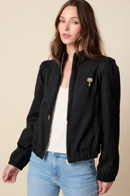 Woman wearing a black jacket with a logo on a beige background