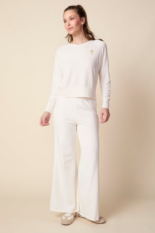 Woman wearing a white sweater and pants on a beige background